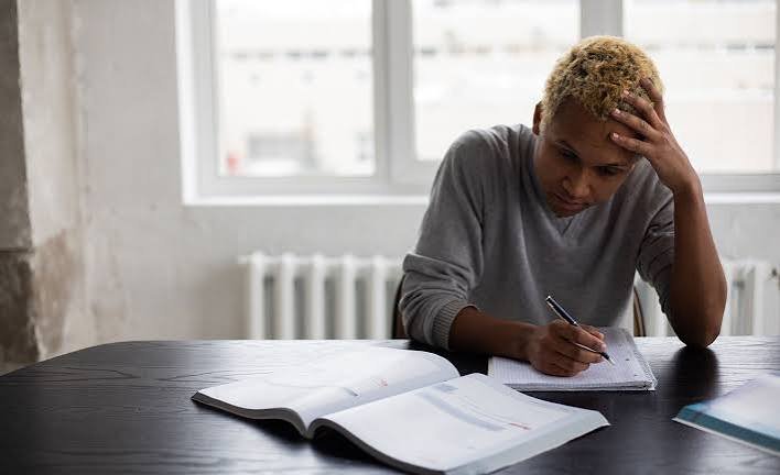young man experiencing stress and overthinking while studying at a desk.
