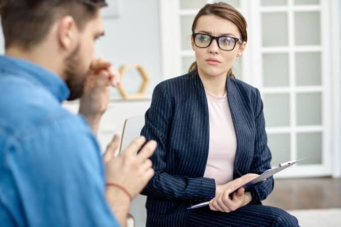 Woman counselor listening to a man during a work and career stress counseling session.